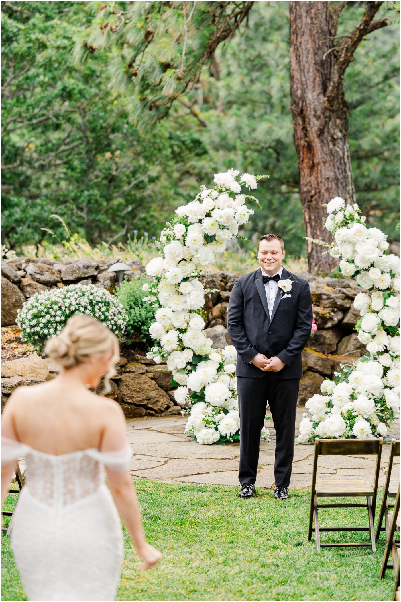 bride and groom first look down aisle with floral arch