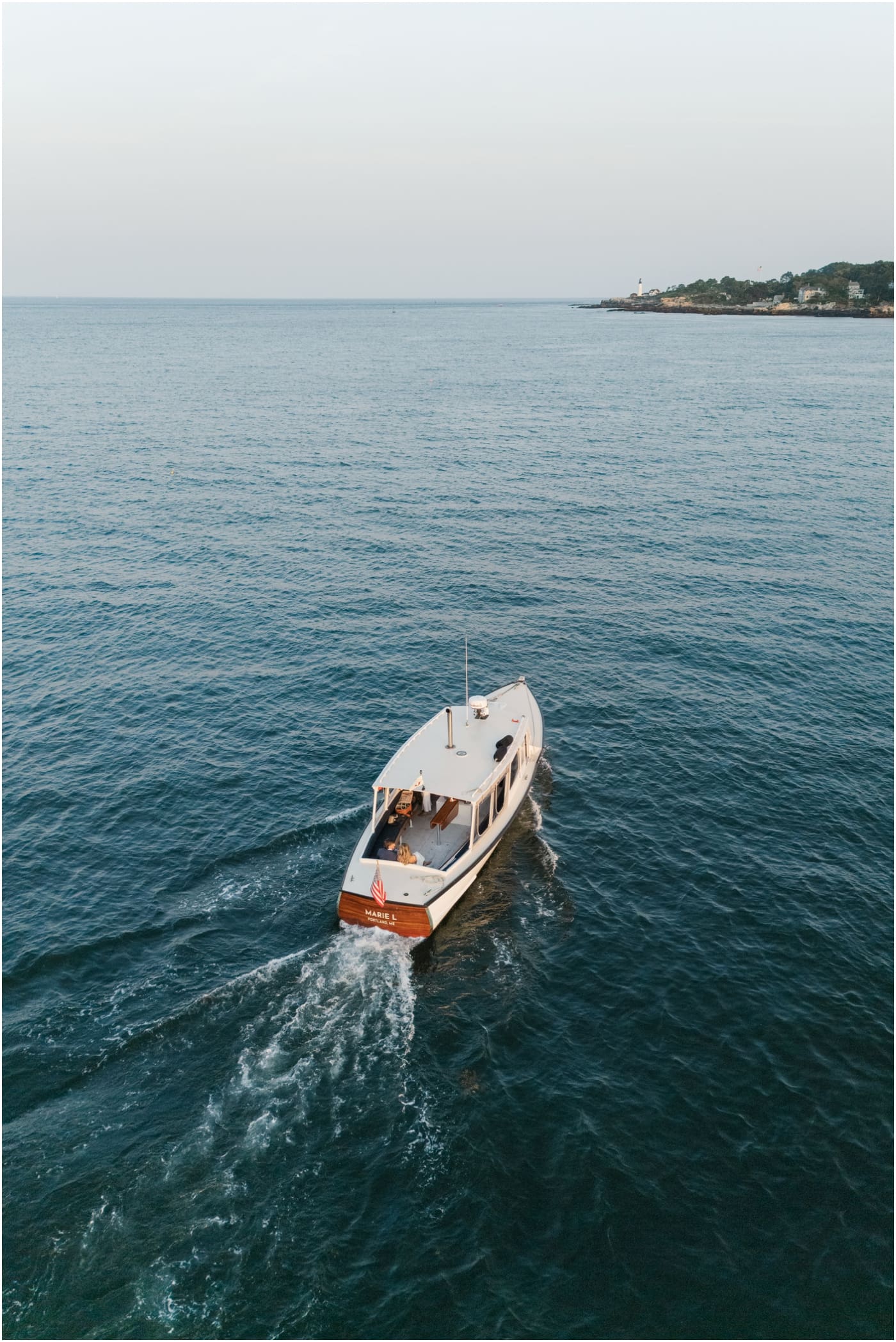 Drone photo of couple on boat with Portland head light in distance