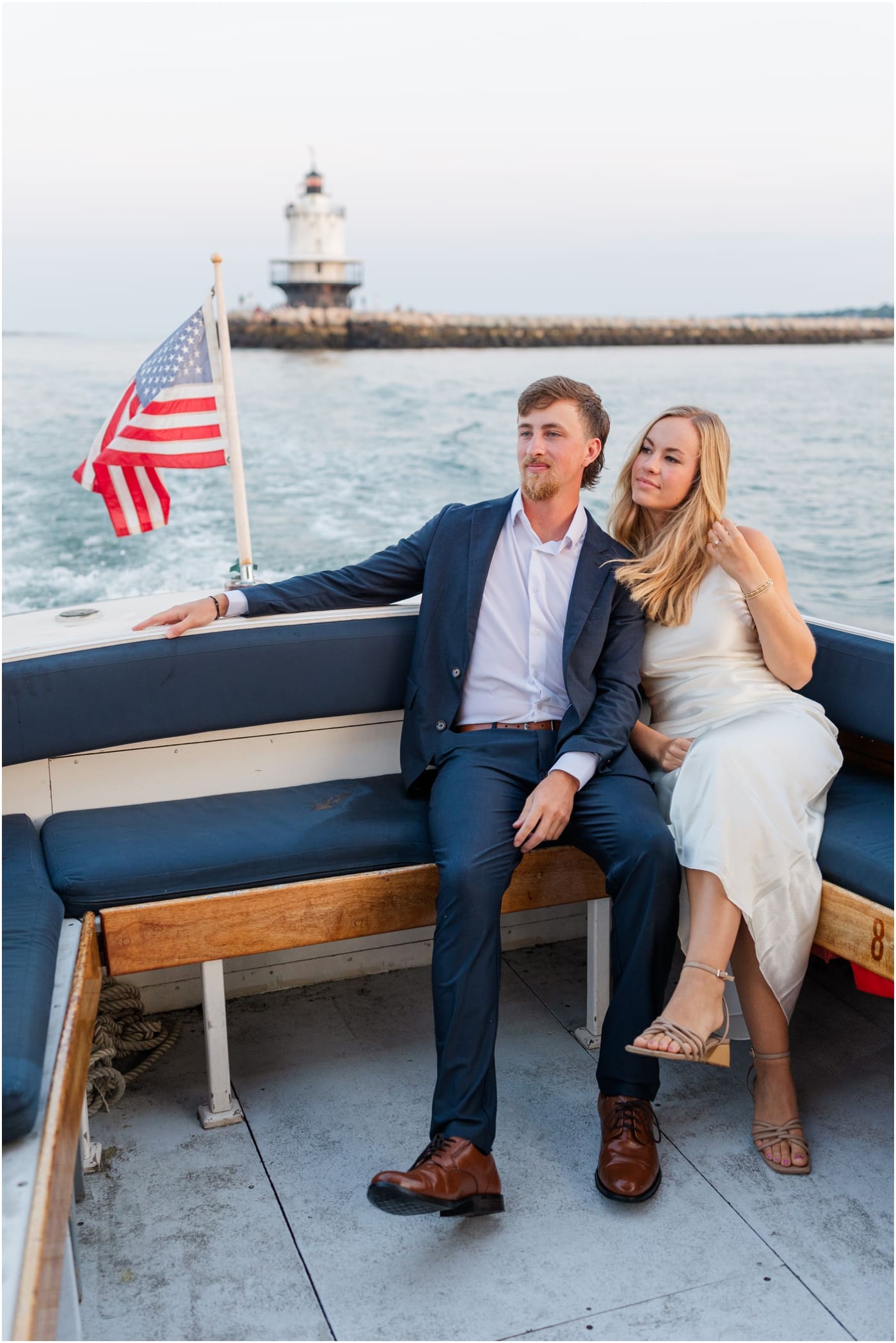 couple on boat in Portland maine with lighthouse behind them