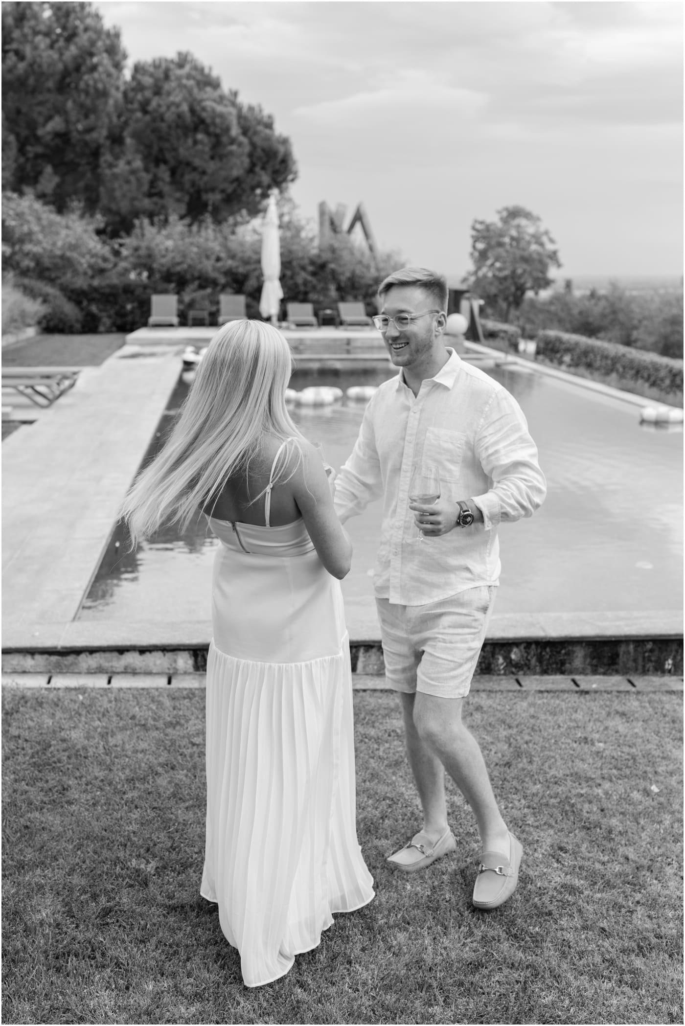 black and white of happy groom spinning bride at their poolside welcome party