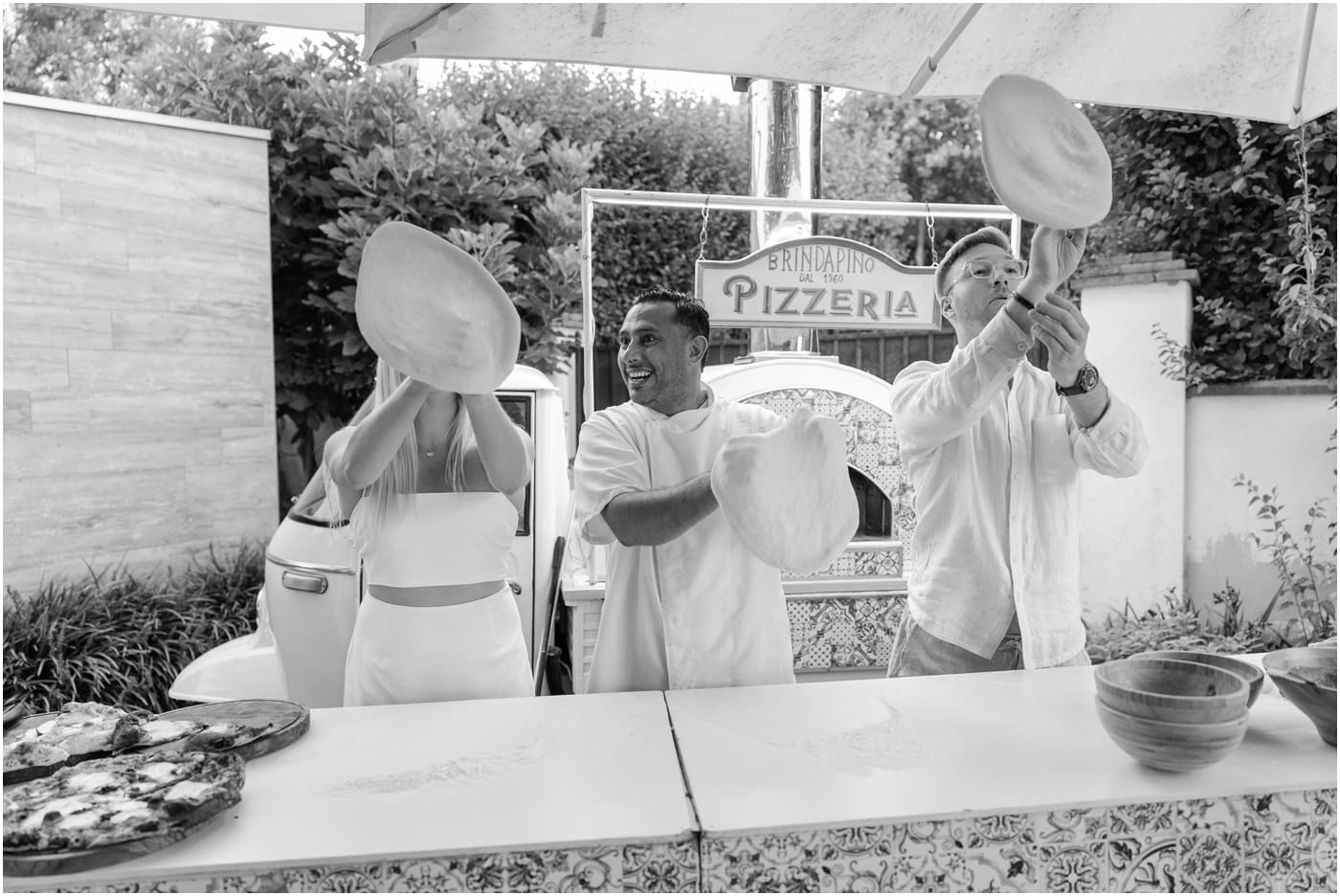 black and white of bride and groom making pizza at their Italian welcome party