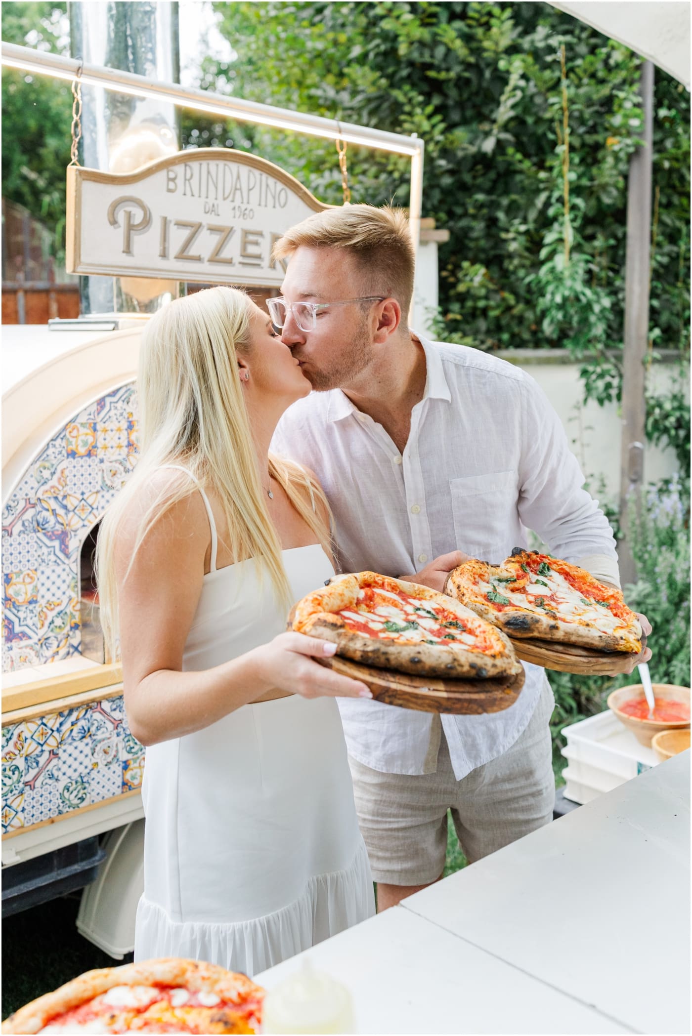 bride and groom kissing with the pizza they made at their Italian welcome party