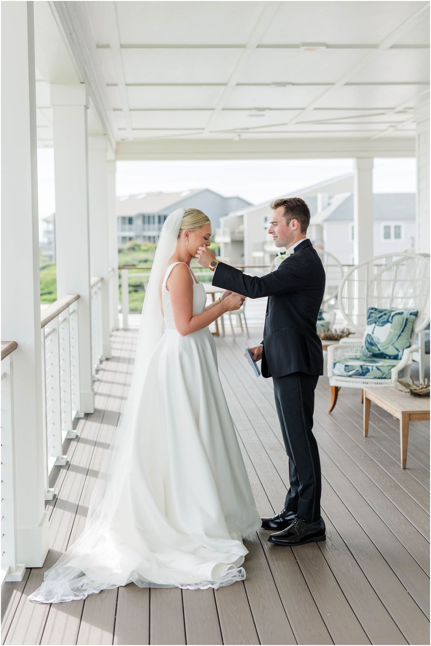 groom wiping away tear during first look at coral bay club