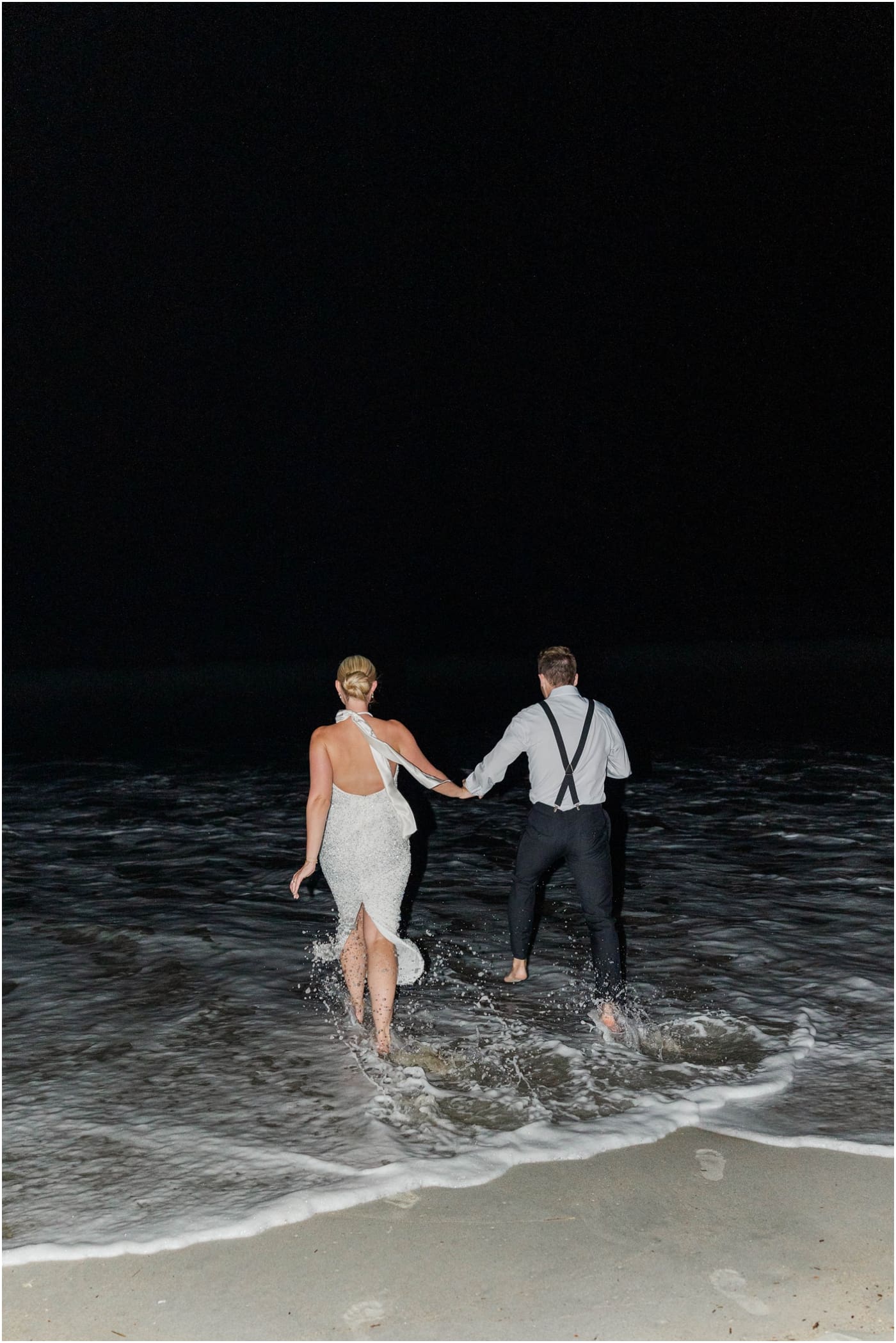 bride and groom running to ocean after their wedding reception at the coral bay club 