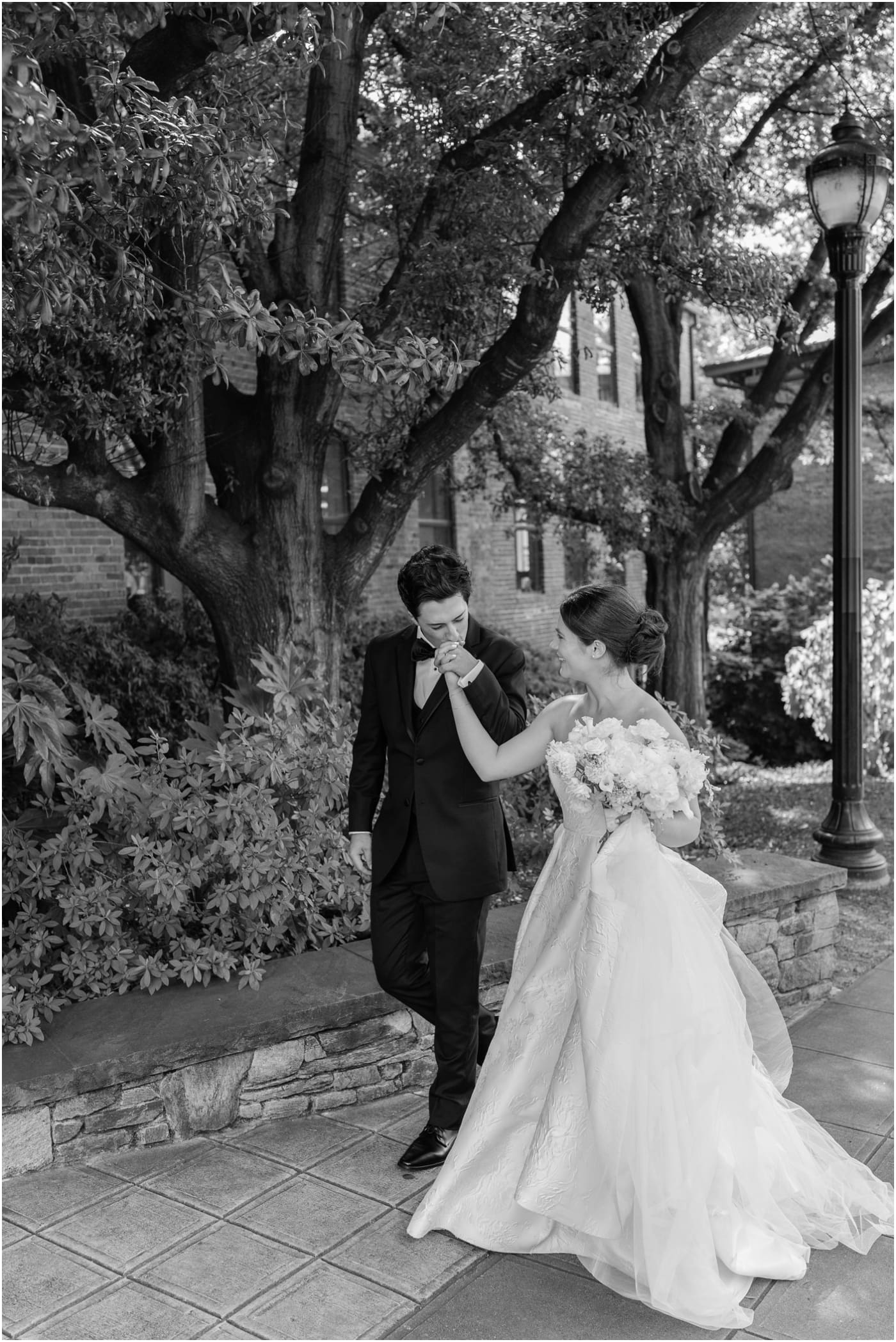 black and white photo of groom kissing brides hand as they walk out from of Huguenot loft 