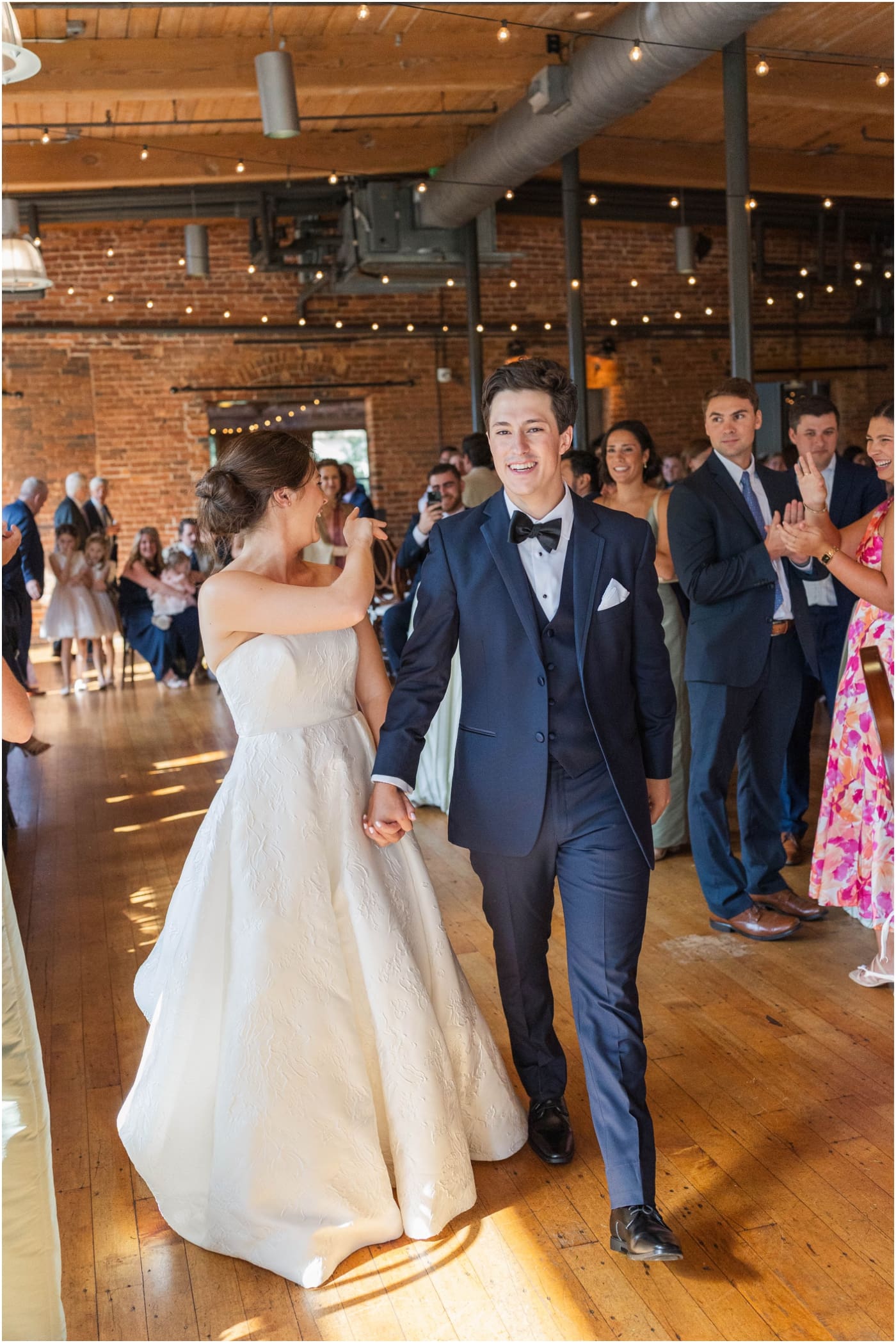 bride waving as she enters wedding reception at Huguenot loft with groom 