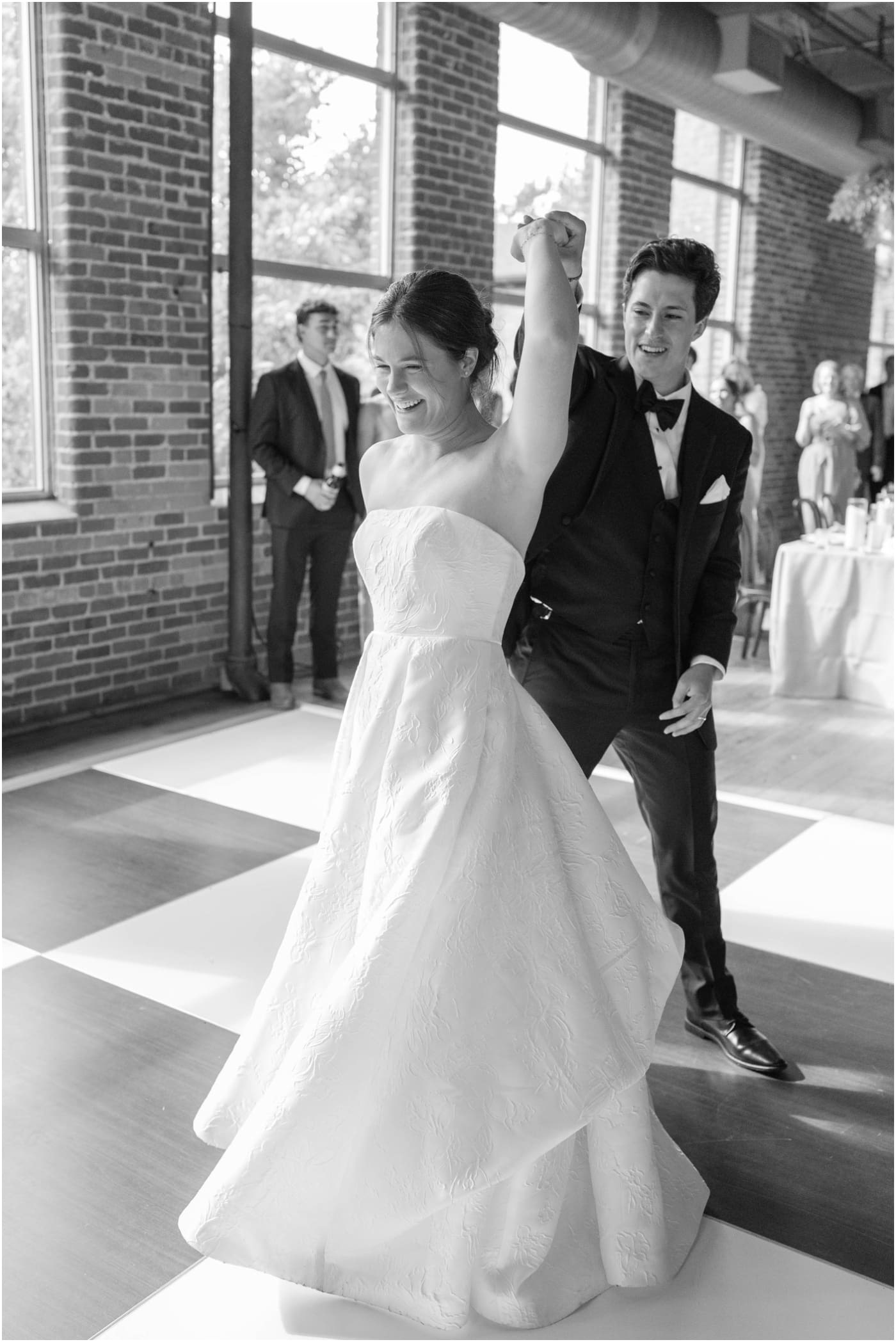 black and white photo of groom spinning bride on checkered dance floor at their Huguenot loft reception 