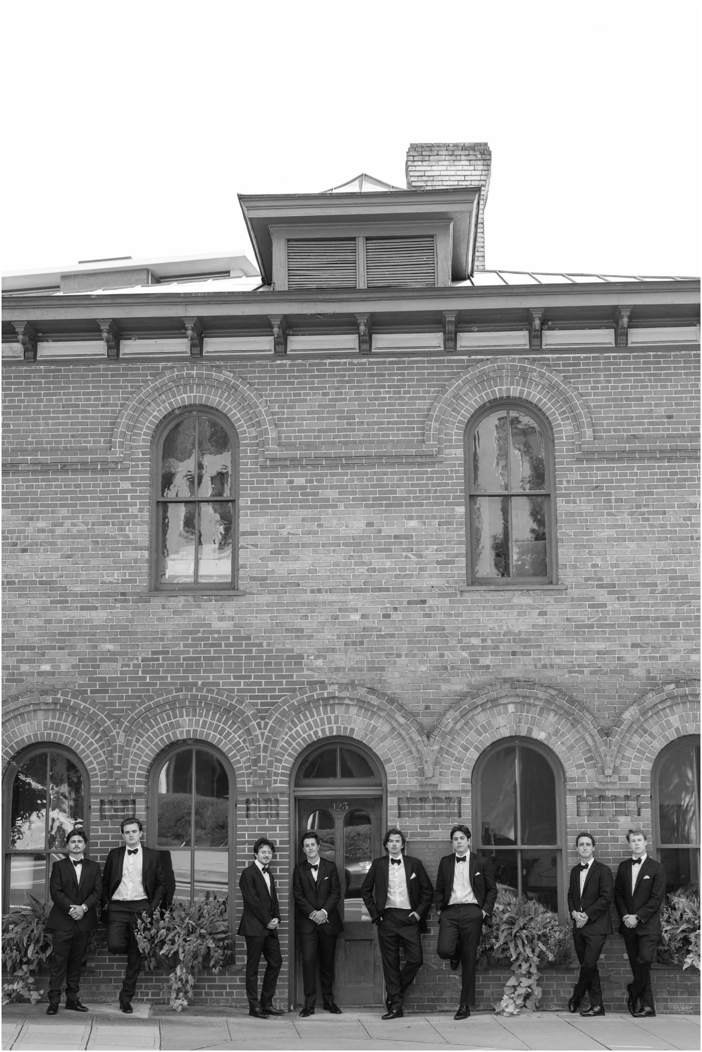 black and white photo of groomsmen posing outside the Huguenot loft in downtown Greenville