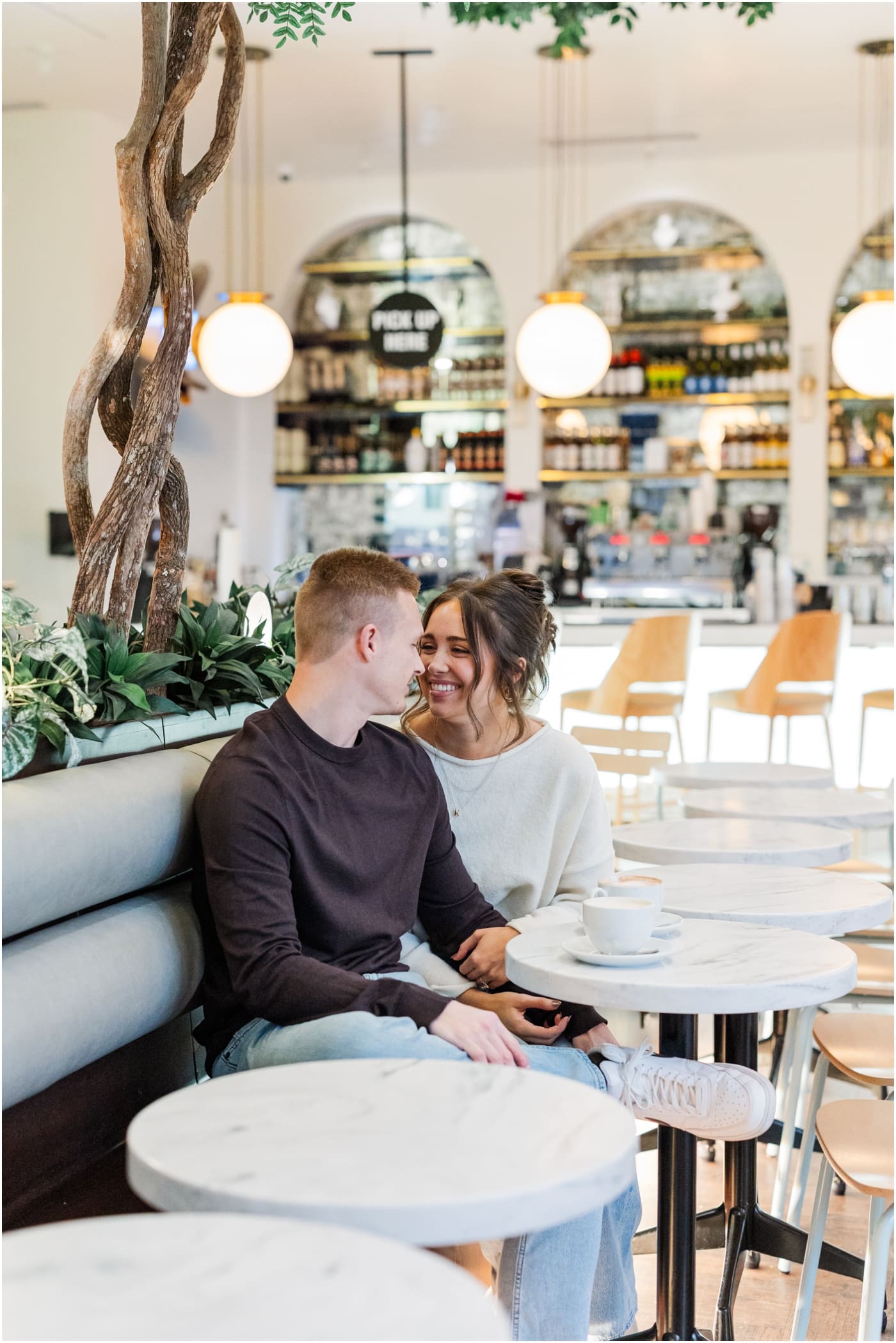 couple sitting in Carmellas during their coffee shop engagement session in Greenville