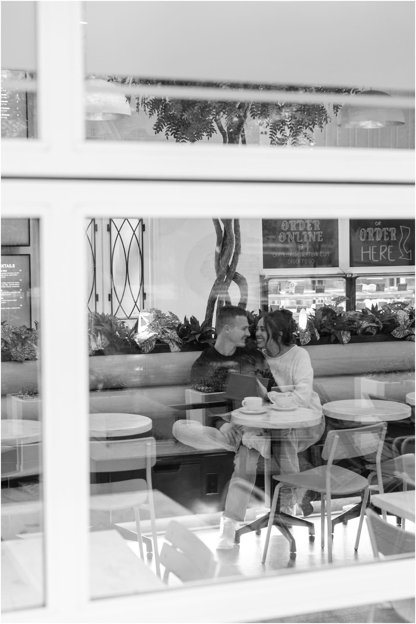 couple sitting in Carmellas during their coffee shop engagement session in Greenville