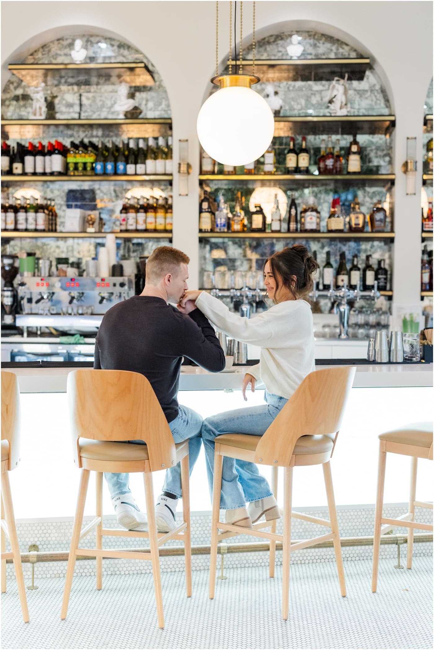 guy kissing girls hand while sitting in Carmellas during their coffee shop engagement session 