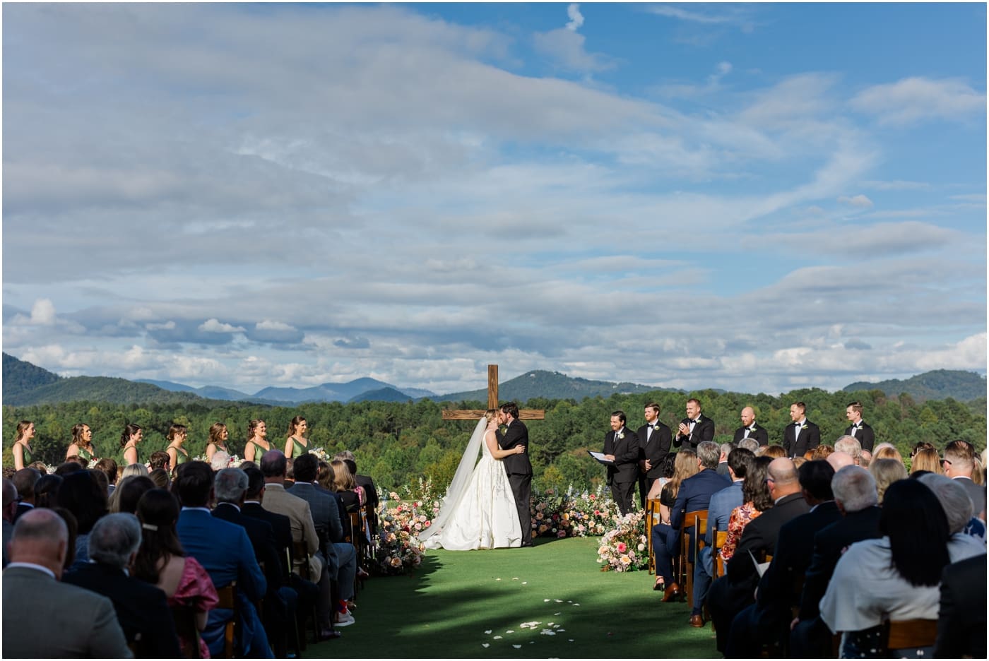 bride and groom share their first kiss with mountains in background at reserve at lake keowee wedding