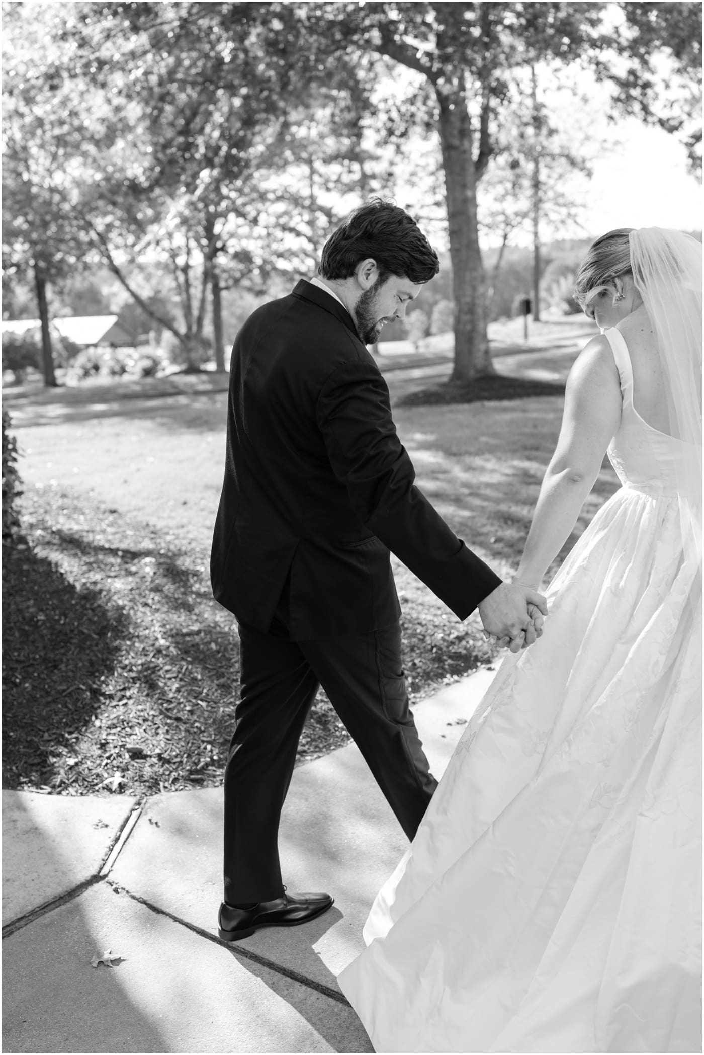 black and white photo of groom admiring brides dress after ceremony at reserve at lake keowee wedding