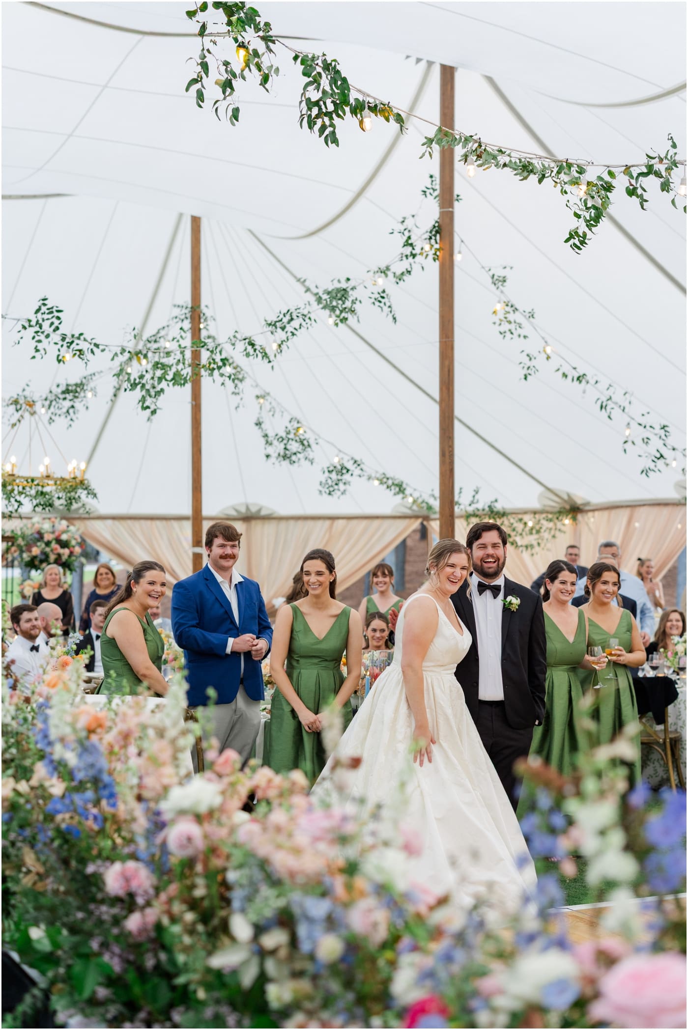 bride and groom laughing surrounded by flowers in their sailcloth tent reception at their reserve at lake keowee wedding