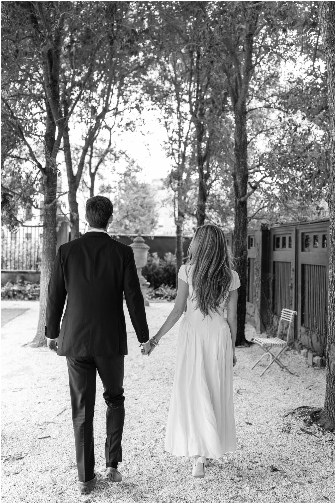 black and white photo of couple holding hands and walking in garden at gibbes museum during engagement session