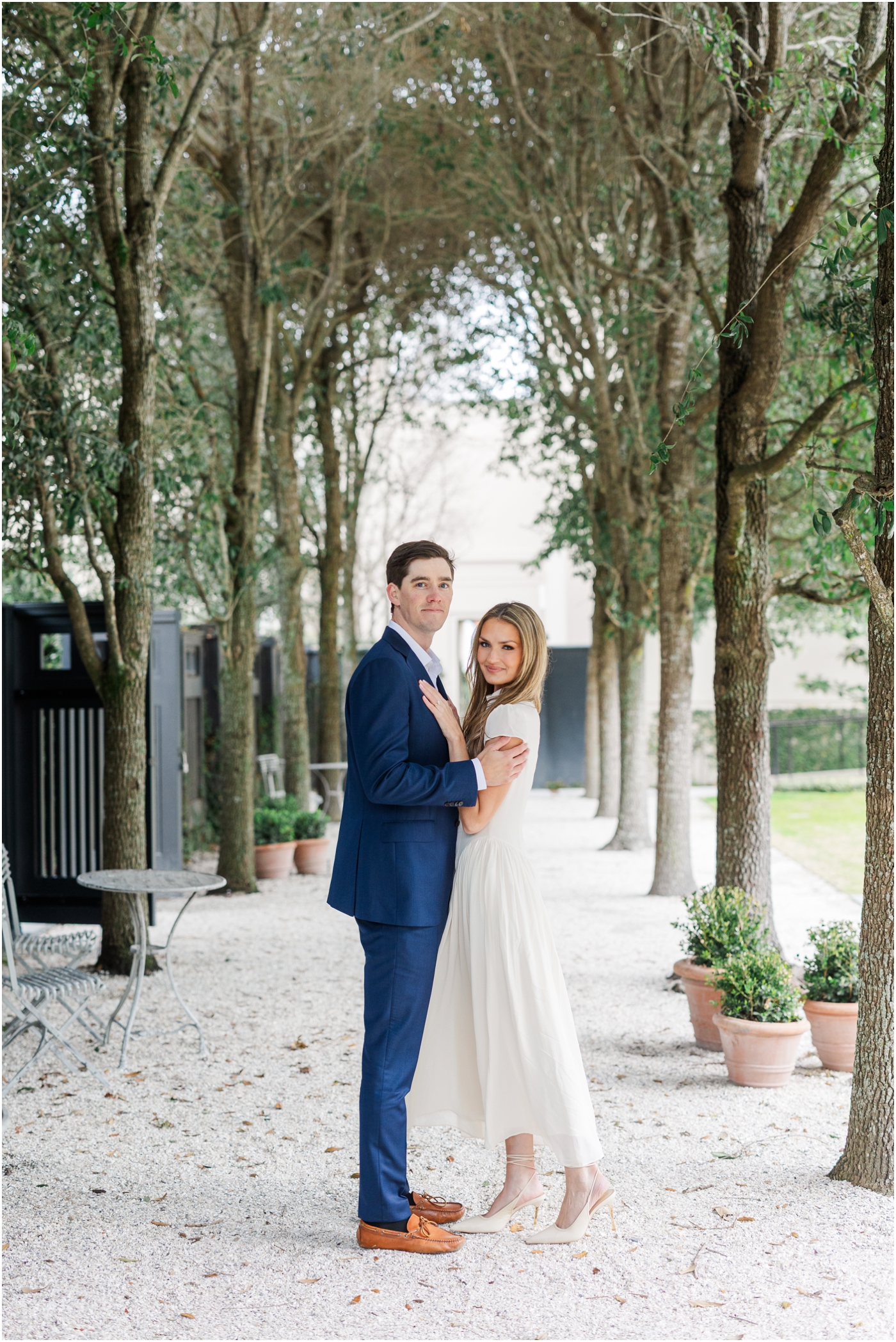 couple smiling at camera in garden during engagement session at gibbes museum 