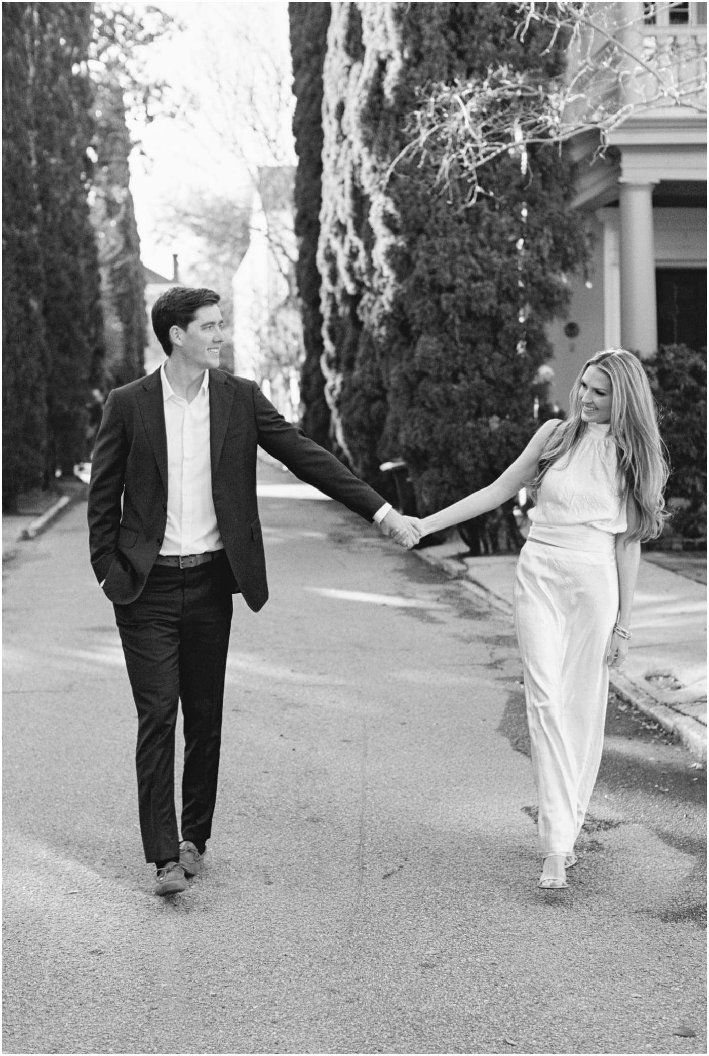 couple holding hands and walking down st Michaels alley in Charleston during engagement session
