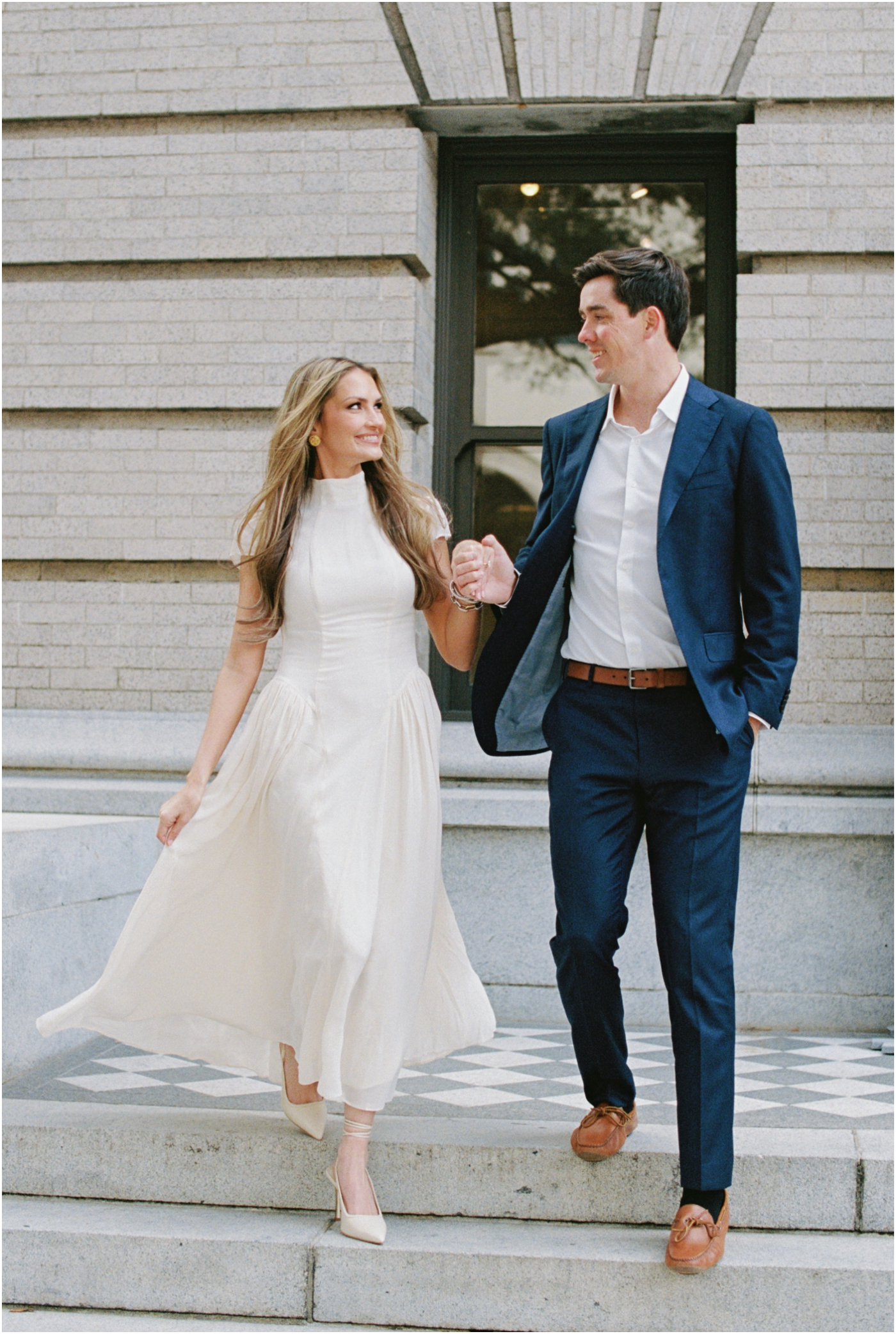 Film photo of couple walking down steps out front of the gibbes museum in Charleston during their engagement session